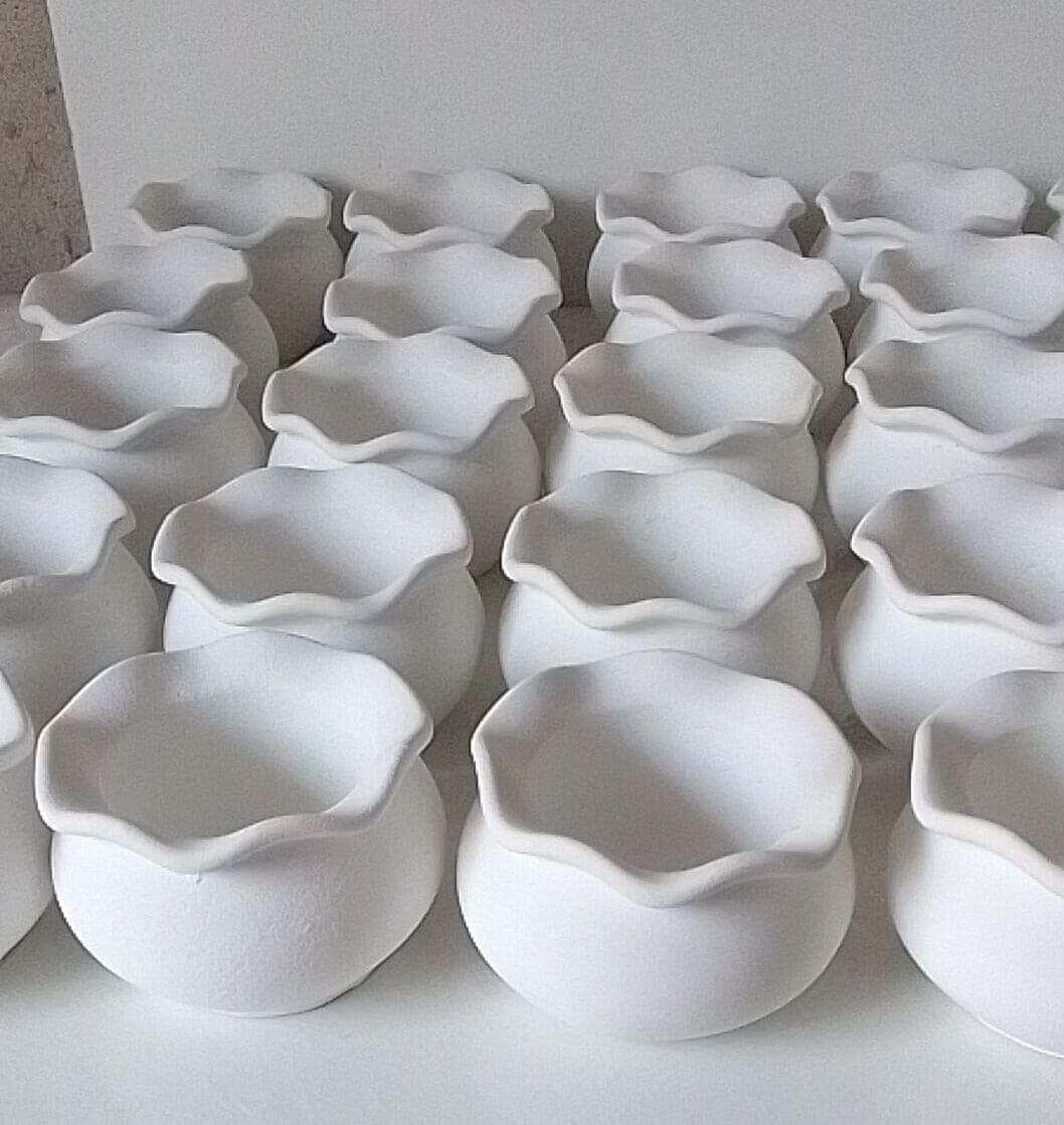 Tanda de macetas de cemento blanco con el borde ondulado, recién terminadas