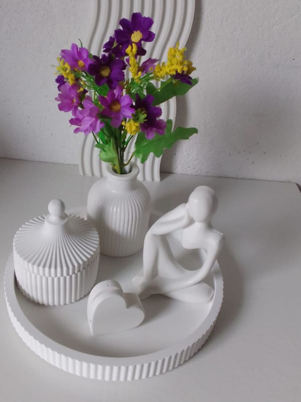 Bandeja redonda con joyero acanalado, florero con flores moradas y figura decorativa
